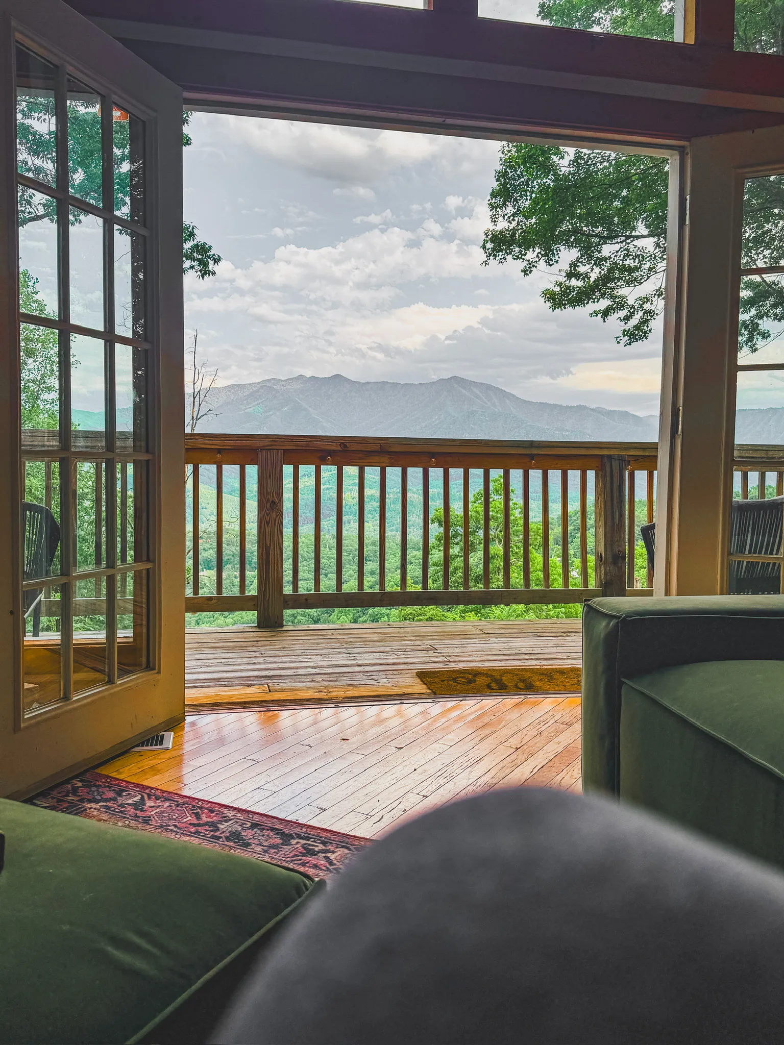 Living room ottoman and open doors to the view at Little Green Cabin