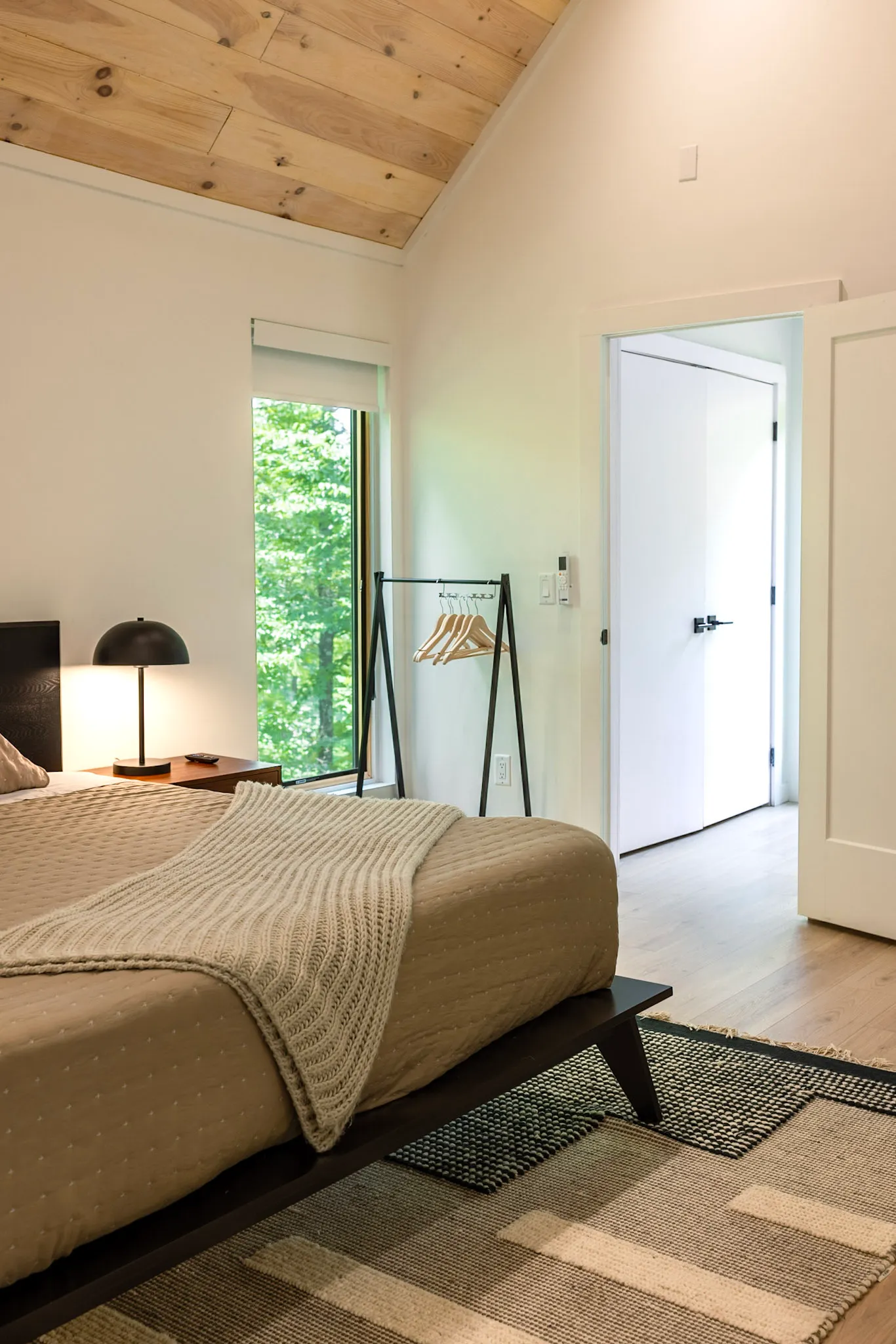 Main bedroom corner with throw blanket and open door at Nordic Haus
