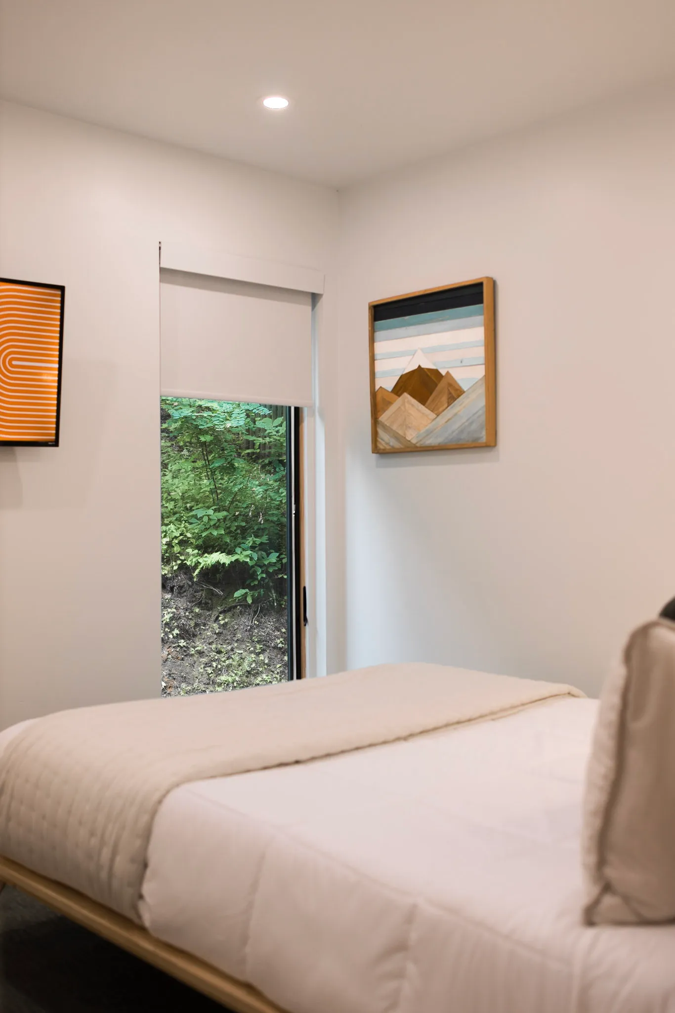 Lower bedroom with bed and framed mountain art at Nordic Haus