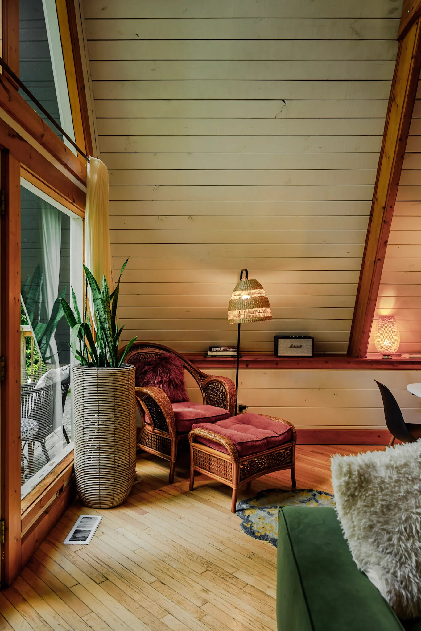 Wicker reading nook by the window at Little Green Cabin