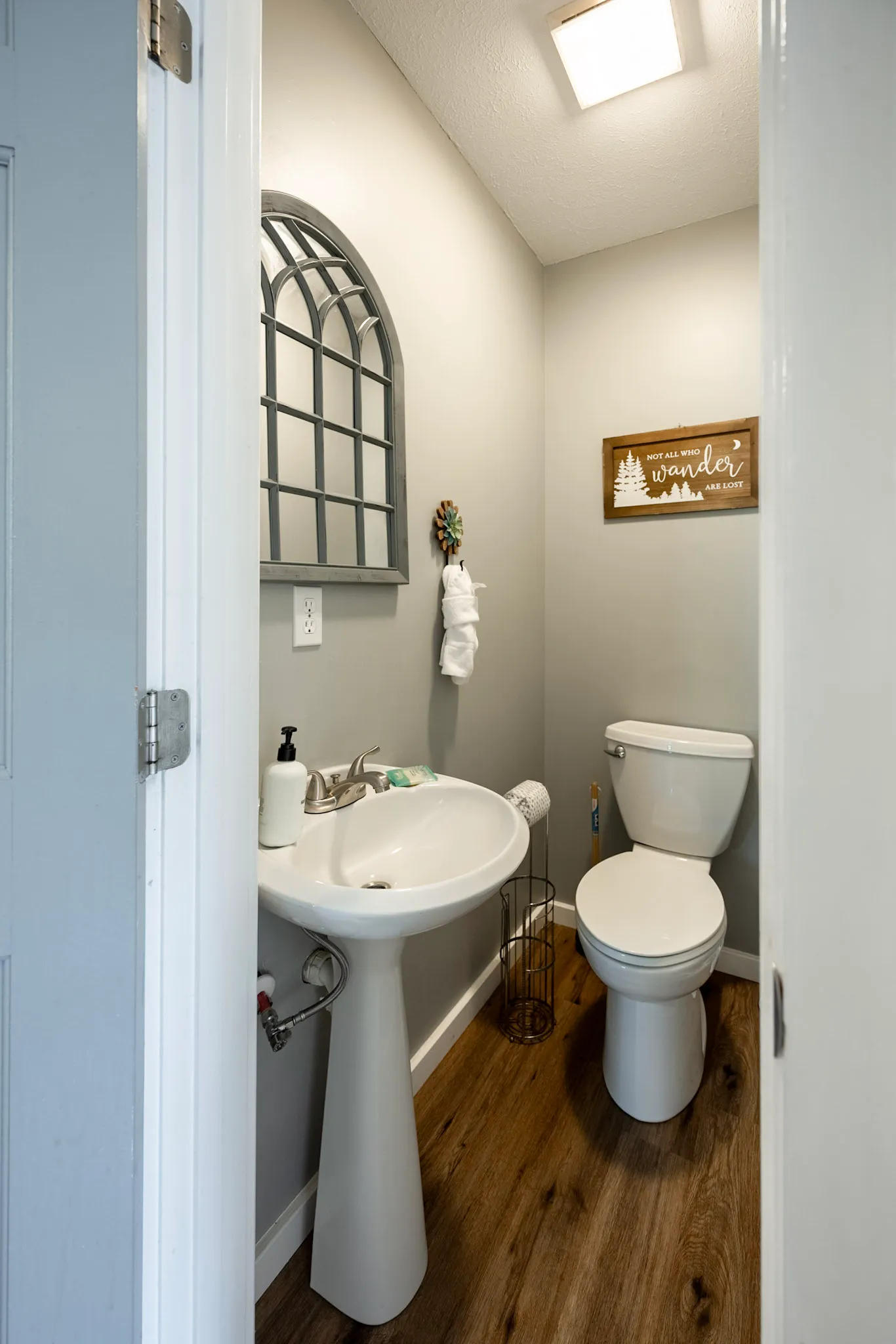 Half bath with pedestal sink and arched mirror at Hygge Blue Chalet