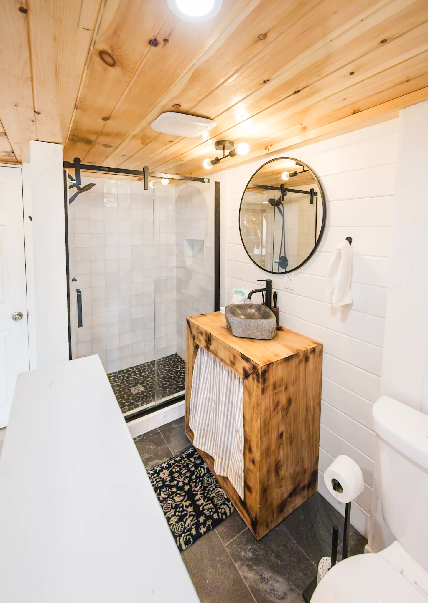 Bathroom one wood vanity with stone vessel sink and glass shower at Après Chalet