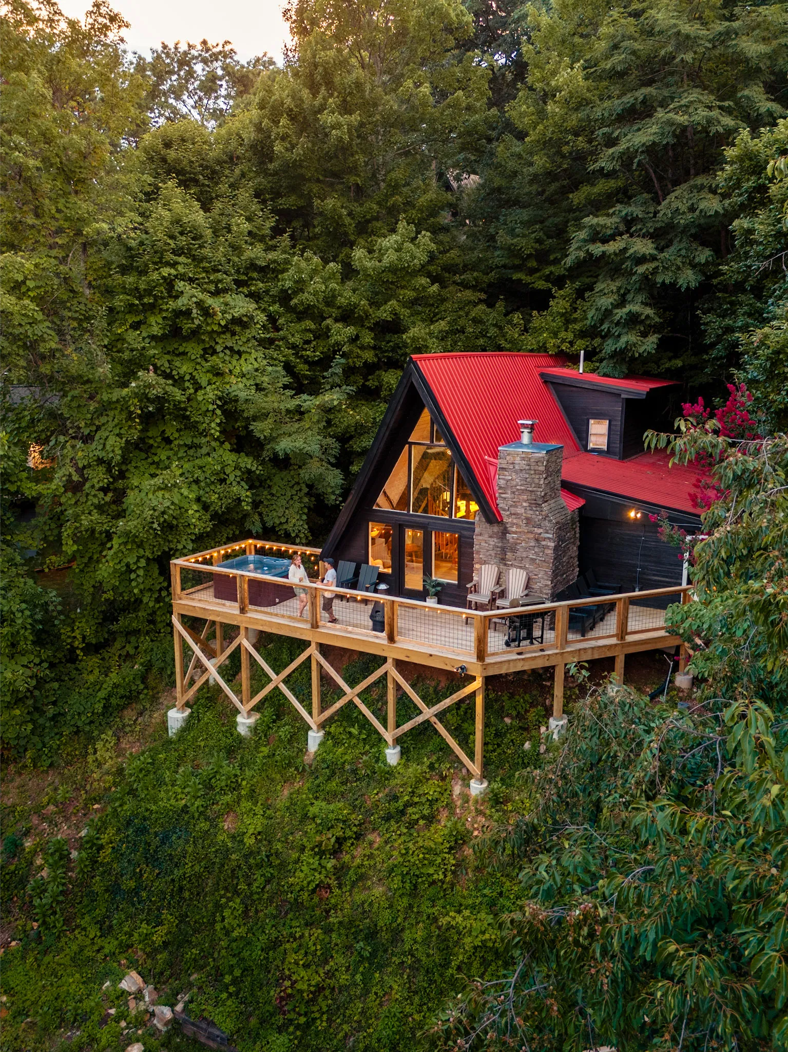 Après Chalet, a red-roofed A-frame with a deck and hot tub, seen from above at golden hour