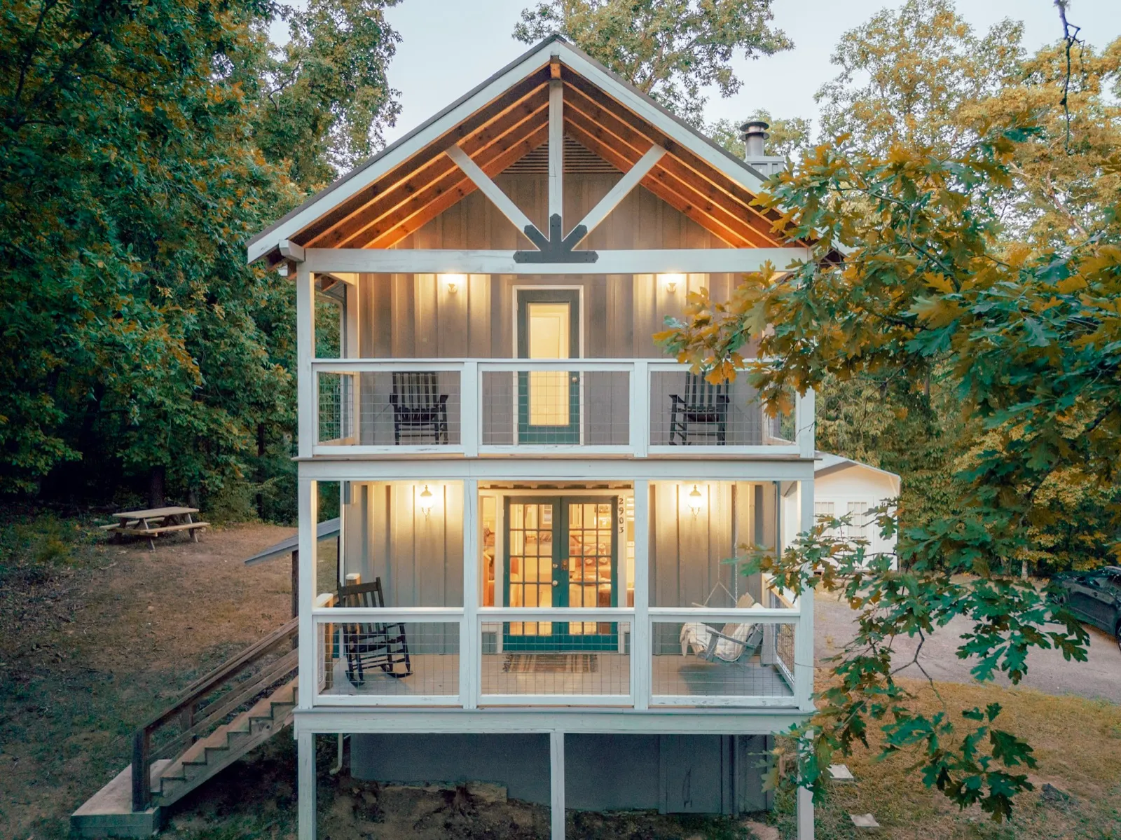 Hygge Blue Chalet, a three-level cabin with stacked porches, lit at dusk