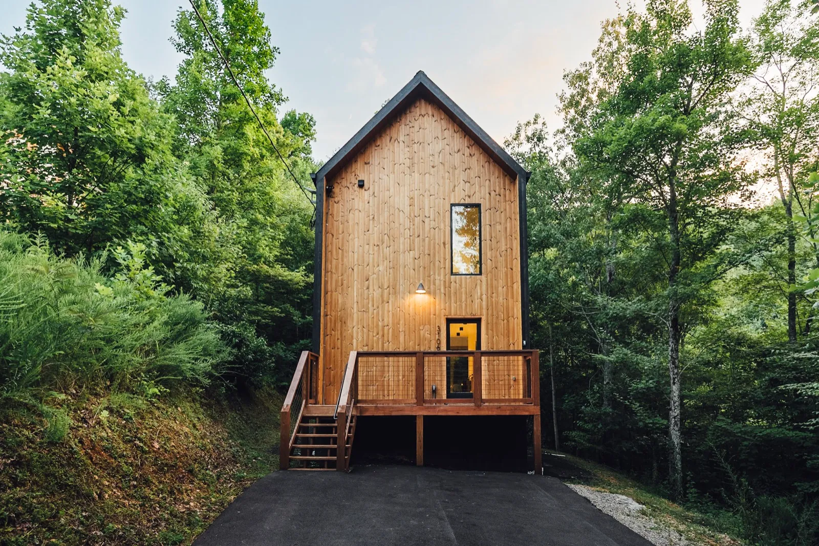 Nordic Haus, a tall modern wood cabin with a steep gable, seen from the driveway